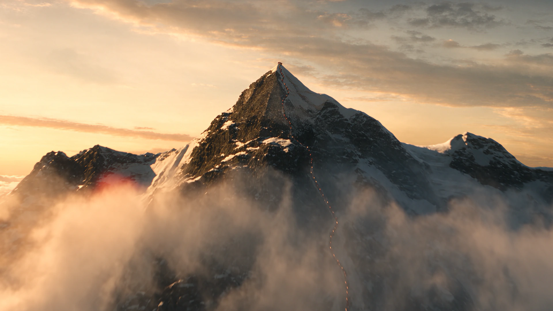 A mountain summit standing clear above a bank of cloud, lit gold along one ridge by a low sun.
